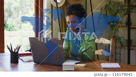 Image of numbers, map over biracial woman talking on cellphone and working on laptop at office Image of numbers, map over biracial woman talking on cellphone and working on laptop at office 116179045