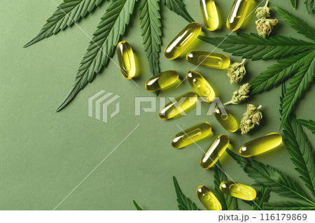 CBD Oil Capsules with Hemp Leaves on Green Textured Background with copy space 116179869