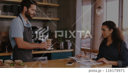 Caucasian male colleague serving coffee, biracial female colleague reading 116179971