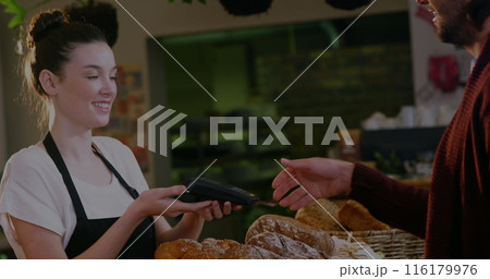 Image of trading boards, caucasian barista handing credit card reader to man to input password 116179976