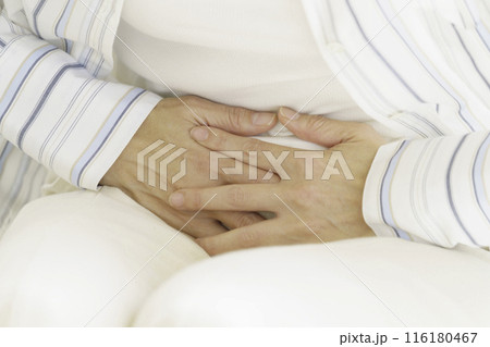 お腹をおさえるミドルエイジの女性の手のアップ 116180467