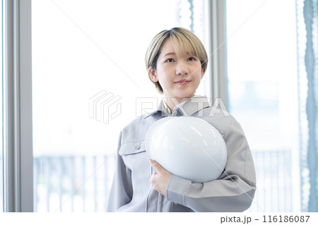 作業服を着てヘルメットを持つ金髪ショートヘアの若い女性(髪色自由、自分らしく働く、職場環境) 作業服を着てヘルメットを持つ金髪ショートヘアの若い女性(髪色自由、自分らしく働く、職場環境) 116186087