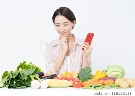 スマホを持って野菜を見るミドルの女性 スマホを持って野菜を見るミドルの女性 116186111