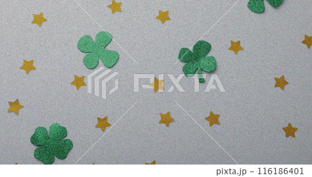 Green clover cutouts and yellow stars decorating grey background Green clover cutouts and yellow stars decorating grey background 116186401