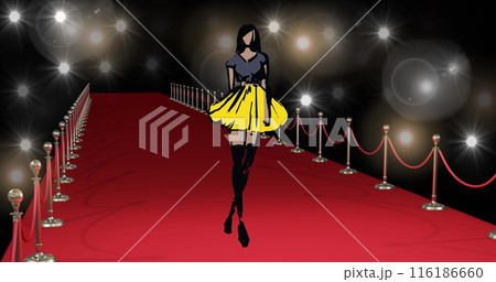 Woman in black and yellow dress walking down red carpet, surrounded by lights 116186660
