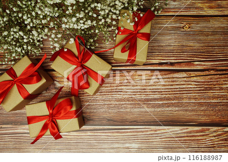 Gift boxes with red ribbon and flower decoration on wooden background 116188987