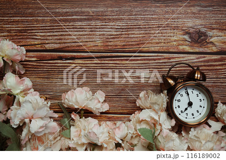 Space copy background with alarm clock and flower decoration on wooden background Space copy background with alarm clock and flower decoration on wooden background 116189002