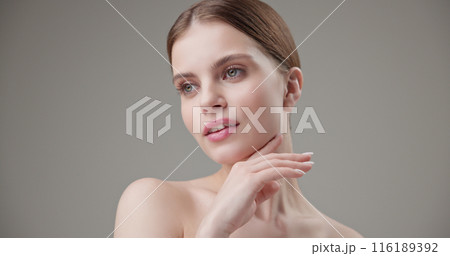 Beauty, health, cosmetics, anti-aging therapy and skin care concept - young beautiful brunette Caucasian woman posing and looking at the camera with a calm confident look like in a mirror 116189392