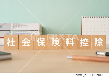 社会保険料控除の文字が入ったブロックが置かれたデスク 116190002