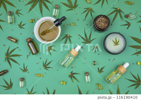 Flat lay composition with hemp oil and hemp leaves on green color background 116190410