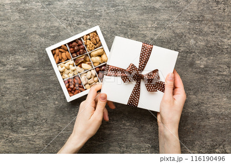 Young woman holding box with different nuts, closeup. Close up, copy space, top view, flat lay. Walnut, pistachios, almonds, hazelnuts and cashews Young woman holding box with different nuts, closeup. Close up, copy space, top view, flat lay. Walnut, pistachios, almonds, hazelnuts and cashews 116190496