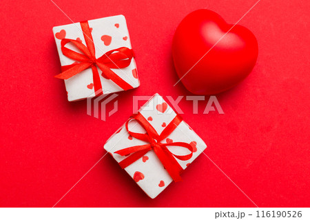 gift box with red bow and red heart on colored background . Top view. Flat lay gift box with red bow and red heart on colored background . Top view. Flat lay 116190526