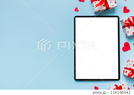 Top view of digital tablet with gift boxes and hearts on colorful background. Tablet with black screen with Holiday decorations gift box top view 116190541