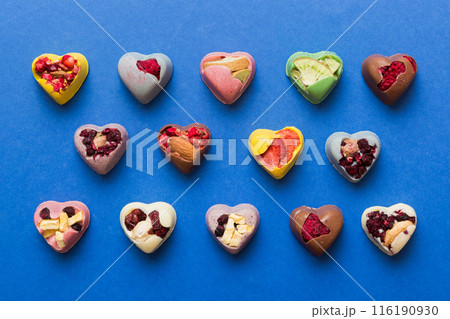 chocolate sweets in the form of a heart with fruits and nuts on a colored background. top view with space for text, holiday concept 116190930