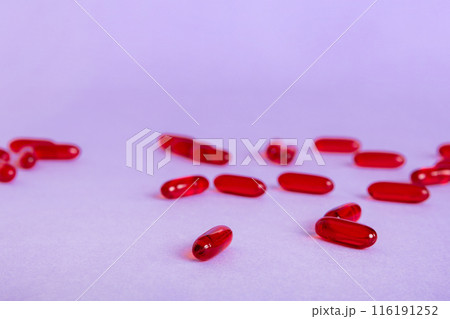 Heap of red pills on colored background. Tablets scattered on a table. Pile of red soft gelatin capsule. Vitamins and dietary supplements concept Heap of red pills on colored background. Tablets scattered on a table. Pile of red soft gelatin capsule. Vitamins and dietary supplements concept 116191252