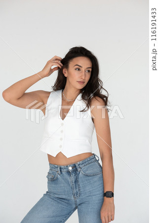 Happy beautiful girl posing in a new hot summer look. Wearing blue jeans and white waistcoat 116191433