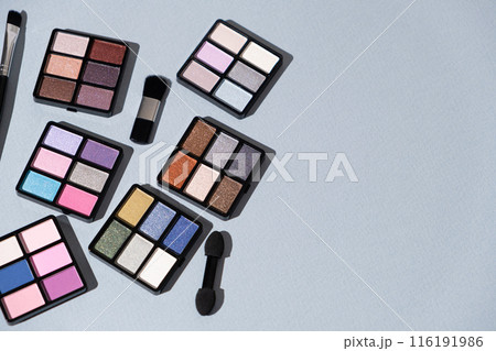 A set of multi-colored eyeshadow and brushes on a blue background. Eye makeup A set of multi-colored eyeshadow and brushes on a blue background. Eye makeup 116191986