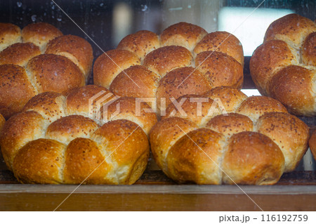 Freshly baked flower shaped bread rolls with a golden crust displayed in a bakery window, in Turkey 116192759