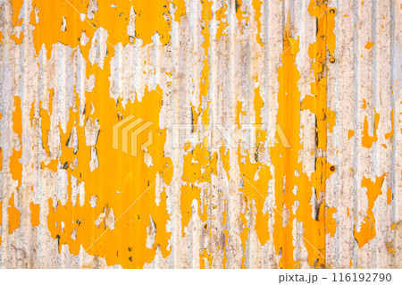 Close up of a weathered corrugated metal surface with peeling yellow paint, revealing rust and wear underneath. Close up of a weathered corrugated metal surface with peeling yellow paint, revealing rust and wear underneath. 116192790
