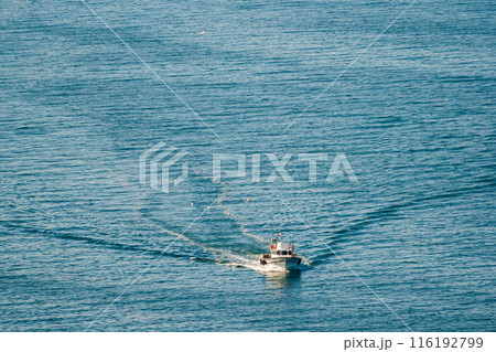 Small boat sailing on a calm blue sea, leaving a trail of waves behind, in Turkey. Small boat sailing on a calm blue sea, leaving a trail of waves behind, in Turkey. 116192799