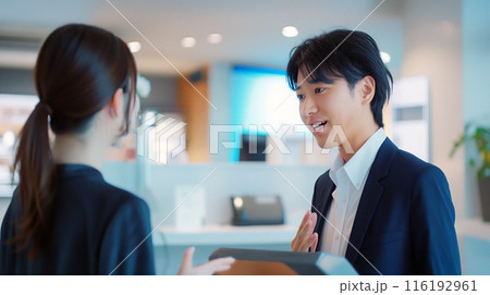 店内で女性に商品説明をしている男性 116192961