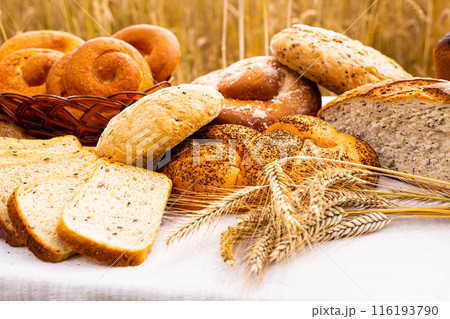 Lot of different flavored bread, wheat, rye, on the table in the field outside 116193790