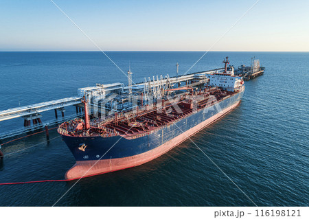 Aerial view of a large oil tanker docked at a pier in the port in process of loading. 116198121