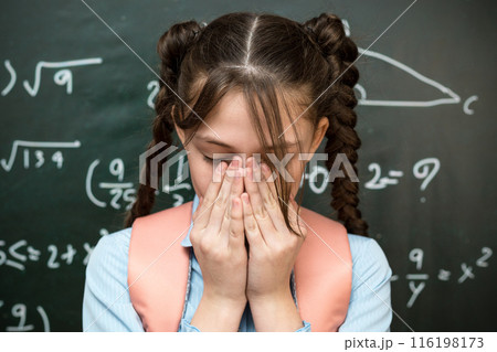 A schoolgirl's eyes hurt from tension, eye fatigue from studying 116198173