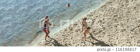 Aerial view on two young people, men and women in motion, playing beach volleyball with determination and motivation, enjoying early morning vibe. Banner 116198817