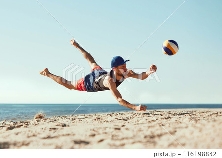 Focused man in sportswear playing beach volleyball by the sea, hitting all in jumbo and falling down in sand. Focused man in sportswear playing beach volleyball by the sea, hitting all in jumbo and falling down in sand. 116198832