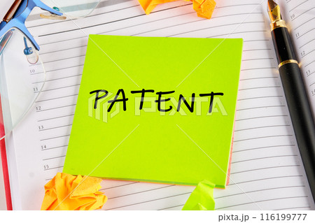 PATENT word written on a light green sticker lying on the notebook PATENT word written on a light green sticker lying on the notebook 116199777