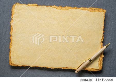 stack of tan toned heavyweight deckle edge paper sheets with a stylish pen 116199906