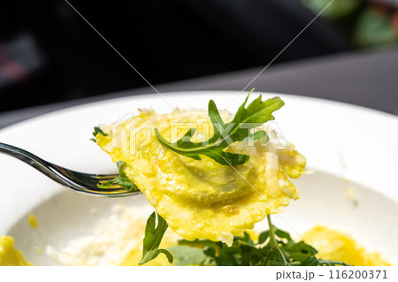 Ravioli, stuffed pasta filled with cheese, arugula topped, grated cheese, served in a lemon zest sauce 116200371