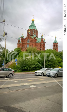 Uspensky Cathedral in Helsinki - red brick church with green blue roof on a cloudy day view from the road with traffic Uspensky Cathedral in Helsinki - red brick church with green blue roof on a cloudy day view from the road with traffic 116201952