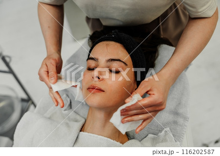 Professional facial skin care. A master massages a woman's face in a beauty salon. Professional facial skin care. A master massages a woman's face in a beauty salon. 116202587