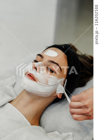 Professional facial skin care. A master massages a woman's face in a beauty salon. Professional facial skin care. A master massages a woman's face in a beauty salon. 116202588