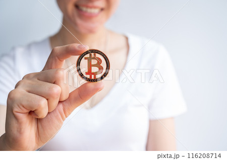 Close up of woman holding a golden Bitcoin token isolated on white background. Bitcoin is one of the popular cryptocurrency, a virtual currency or a digital currency. 116208714