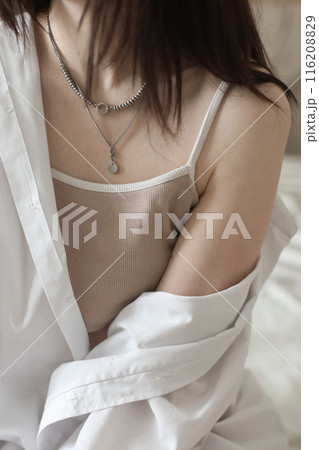 Close-up of Young woman in lingerie and white shirt sit on bed indoors at home in the morning after waking up, back view. Relaxing , Cozy, good morning, comfort, intimacy concept. Close-up of Young woman in lingerie and white shirt sit on bed indoors at home in the morning after waking up, back view. Relaxing , Cozy, good morning, comfort, intimacy concept. 116208829