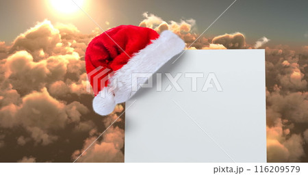 Digital composite of Santa hat with white card and clouds 116209579