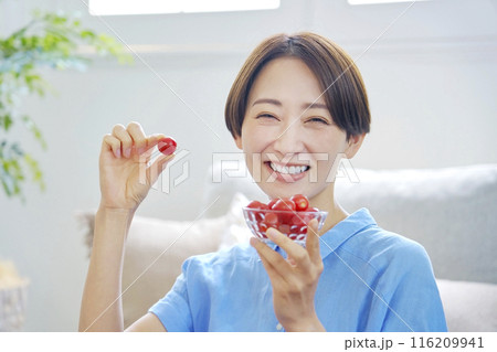 自宅でミニトマトを食べる女性 カメラ目線 自宅でミニトマトを食べる女性 カメラ目線 116209941