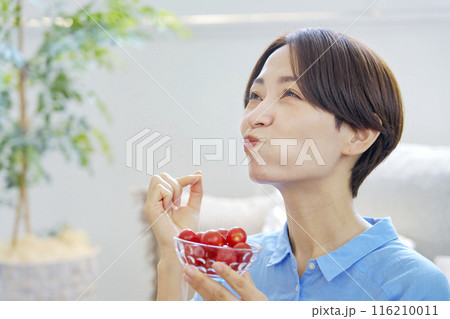 自宅でミニトマトを食べる女性 自宅でミニトマトを食べる女性 116210011