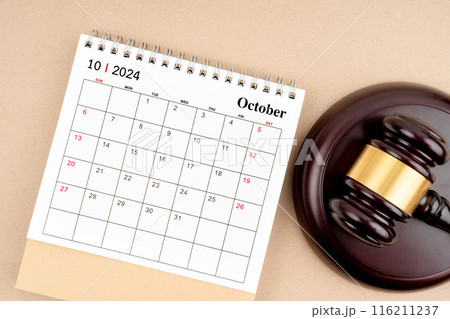 Desk calendar for October 2024 and judge's gavel on brown background. 116211237