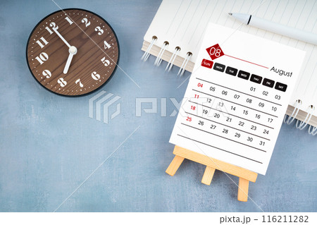 2024 August calendar page and wooden clock on wooden background. 2024 August calendar page and wooden clock on wooden background. 116211282