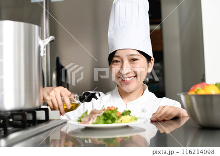 オリーブオイルをサラダにかける女性料理人 116214098