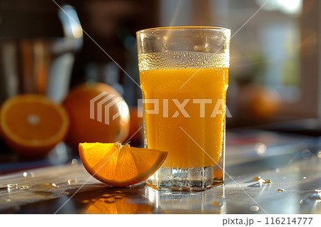A refreshing glass of fresh orange juice placed on a table with a sliced orange wedge, ready for a healthy morning breakfast. 116214777