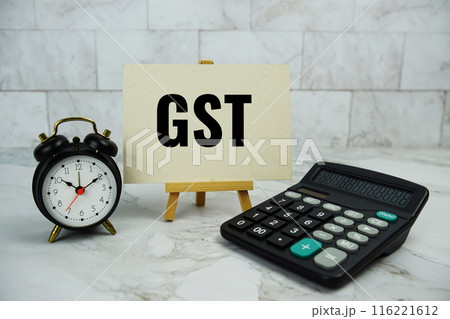 GST, goods and services tax text written on paper card with calculator and alarm clock on marble background 116221612