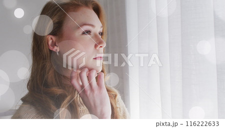 Image of light spots over caucasian woman looking through window 116222633