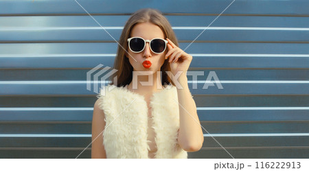 Modern stylish young woman blowing kiss in white glasses, fashionable girl posing on gray background Modern stylish young woman blowing kiss in white glasses, fashionable girl posing on gray background 116222913