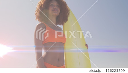 Image of lights over african american woman holding surfboard Image of lights over african american woman holding surfboard 116223299