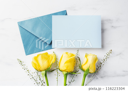 Blue card with envelope and yellow roses on white table background, father's day gift and card, top view 116223304